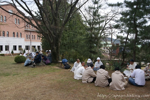 순례 참여 수도자들이 수도원의 뜰에 앉아 준비해온 도시락으로 점심을 먹고 있다