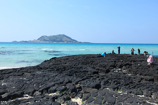 해변 한쪽에는 검은 암반이 있어 푸른 바다빛깔과 대조적이다.