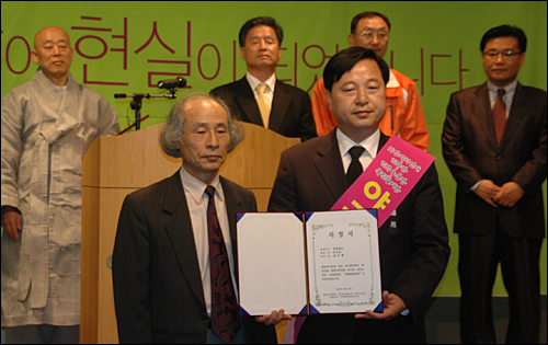김두관 전 행정자치부 장관이 안승욱 희망자치만들기경남연대 공동대표로부터 '야권단일후보 지정서'를 받은 뒤 들어보이고 있다.