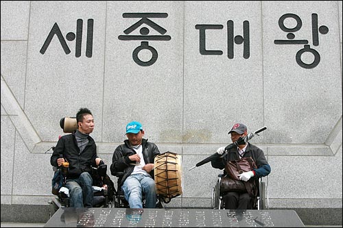 '북채' '신문지 뭉치'를 차례로 뺏긴 장애인들이 '우산'으로 북을 치고 있다.