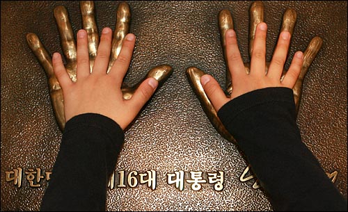 한 어린이가 고 노무현 전 대통령의 손바닥 모형에 자신의 손을 얹어 보고 있다.