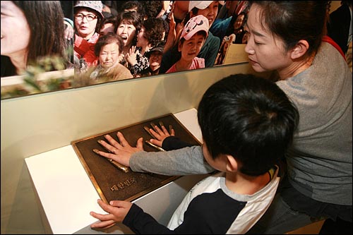 한 가족이 고 노무현 전 대통령의 손바닥 모형에 자신의 손을 얹어 보고 있다.