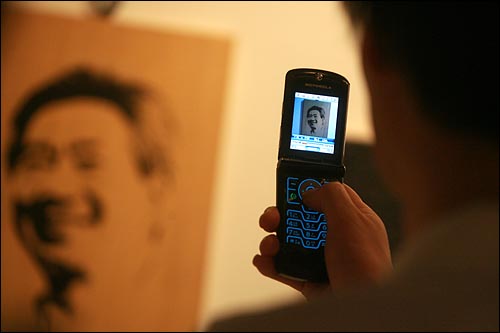관람객들이 노무현 대통령의 모습을 휴대폰 사진으로 담고 있다.