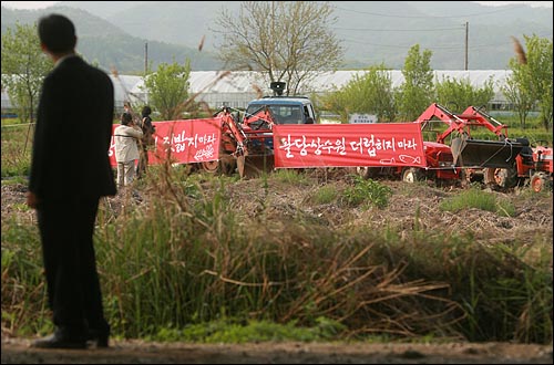  지난 11일 오전 경기도 양수리 두물머리에서 4대강 사업으로 농지를 잃게 될 위기에 처한 농민들과 환경단체 회원들이 청와대와 경기도청을 향해 농기계를 앞세우고 도보순례를 준비하는 가운데, 멀리서 경찰이 지켜보고 있다.