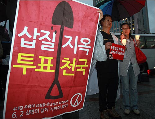  18일 저녁 서울 종로구 보신각 앞에서 열린 '5.18 30주년 기념 집회'와 '반성촛불페스티벌'에 참가한 시민들이 6.2지방선의 투표 참여를 독려하는 현수막과 촛불을 든 채 공연을 즐기고 있다.