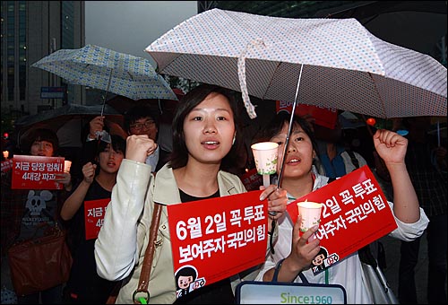 18일 저녁 서울 종로구 보신각 앞에서 열린 '5.18 30주년 기념 집회'와 '반성촛불페스티벌'에 참가한 시민들이 6.2지방선의 투표 참여를 독려하며 손피켓과 촛불을 들어보이고 있다.
