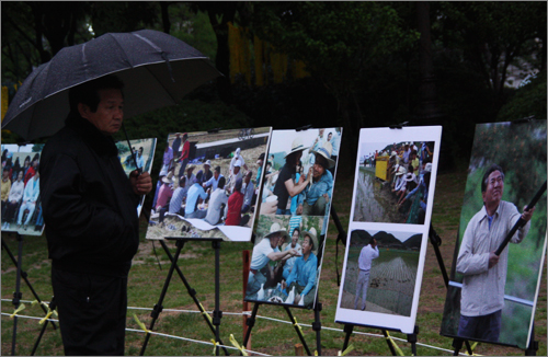 고 노무현대통령 서거 1주기를 맞아 분향소가 마련된 서대전시민공원에서 한 시민이 우산을 쓴 채로 노무현 대통령의 생전 활동 모습이 담긴 사진을 바라보고 있다.