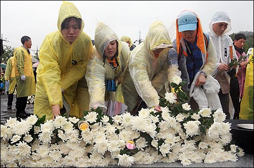 고 노무현 전 대통령 서거 1주기를 맞은 23일 오후 경남 김해시 봉하마을에서 추모객들이 추모식을 마친 뒤 묘역을 찾아 헌화를 하고 있다.