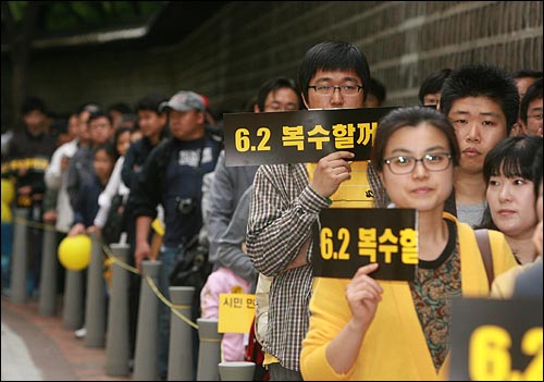 고 노무현 전 대통령 1주기를 맞은 23일 오후 덕수궁 대한문앞에 마련된 시민분향소에 헌화하기 위해 덕수궁 돌담길을 따라 길게 줄을 선 시민들이 '6.2 복수할꺼야'가 적힌 손피켓을 들고 있다.