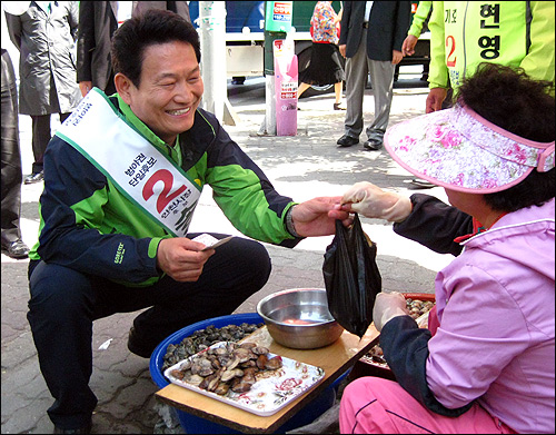 송영길 민주당 인천시장 후보가 1일 오전 학익사거리 유세 과정에서 만난 노점상에게 조갯살을 구입하고 있다.