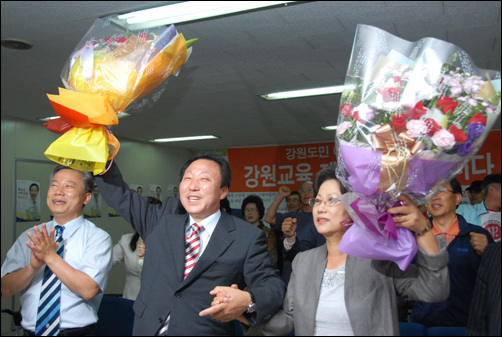 민병희 강원 교육감 당선인 부부가 축하 꽃다발을 받고 손을 흔들어 답례하고 있다.