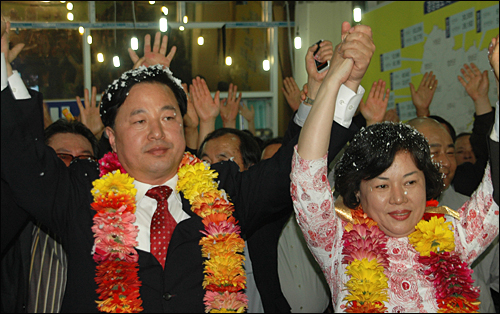 무소속 김두관 경남도지사 후보가 부인 채정자씨와 함께 3일 오전 0시경 꽃다발을 목에 걸고 손을 들어 보이고 있다.