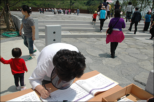 봉하마을 고 노무현 대통령 묘역 앞에 있는 방명록에 참배객들이 기록하고 있다.