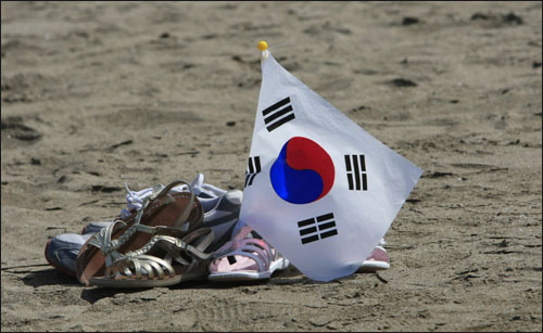 태극기와 신발. 관광객이 물놀이를 즐기는 사이 태극기와 신발만 덩그러니 남아 모래사장을 지키고 있다.