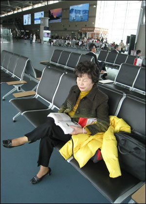 출국 전 공항에서 가이드북을 읽고 있는 어머니 