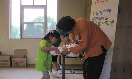 제3회 더불어함께 입학식에 참가한 박소희양이 김순래 일일교장선생님으로부터 기념 선물을 받고 있다.
