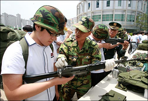 소총 다루는 법 교육받는 고등학생들 현역군인들이 학생들에게 소총 사용법을 교육하고 있다.