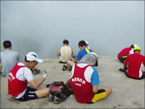 짙은 구름으로 뒤덮인 사패산 정상에서 잠시 휴식을 취하고 있는 참가자들. 