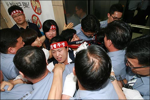KB국민은행 지부 노조원들이 주주총회장으로 올라가는 승강기를 타려다, 저지하는 경비원들과 몸싸움을 벌이고 있다.