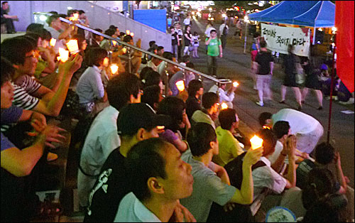23일 저녁 서울역 광장에서 열린 고 황민웅, 고 연제욱 씨 추모제에서 참석한 시민들이 촛불을 들고 앉아 있다.