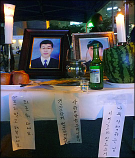 23일 저녁 서울역 광장에서 열린 고 황민웅, 고 연제욱 씨 추모제에 한 켠에 마련된 영정사진과 제사상. 아래의 종이는 유족들이 직접 작성한 것이다.