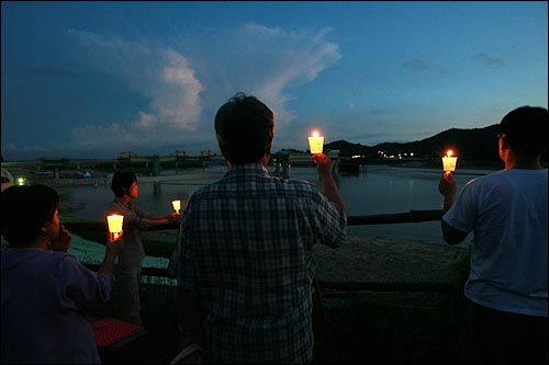 25일 밤 환경연합 상황실에서 시민들이 촛불을 들고 농성자들이 있는 이포보를 바라보고 있다.