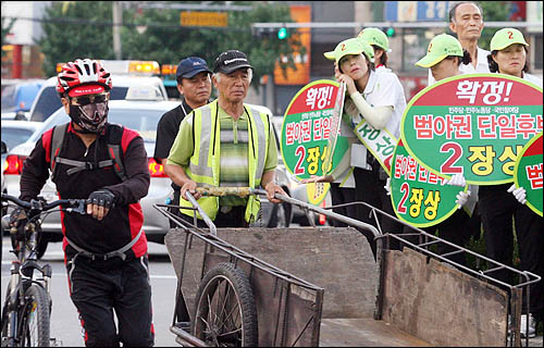 7.28 재보선의 최대 승부처인 서울 은평을 지역의 야권 단일후보로 민주당 장상 후보가 확정된 가운데 26일 은평구 물빛공원을 지나던 구민들이 야3당의 합동유세를 지켜보고 있다.