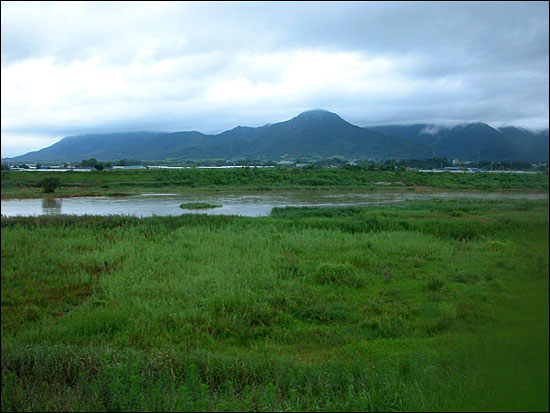 영산강 강변 풍경. 멀리 산 위로 검은 구름이 짙게 내려 앉아 있다.