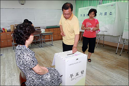 7.28 재·보궐선거일인 28일 오후 서울 불광동 불광초등학교에 마련된 제3투표소에서 유권자가 기표용지를 투표함에 넣고 있다.