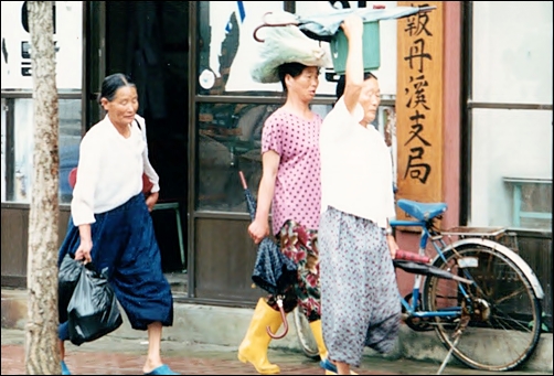  경남 산청군 단계 장날 풍경. 시골 아주머니들이 장을 향해 빠른 걸음을 하고 있는데요. 중앙지 지국 간판이 눈길을 끕니다. 전날 비가 내려서인지 우산을 하나씩 들고 있군요. 
