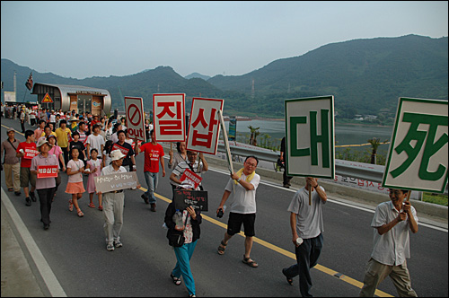 31일 오후 시민들이 '4대강사업 반대' 등의 피켓을 들고 함안보 공사장 앞을 지나고 있다.