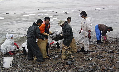 유조선-어선 충돌 사고로 흘러온 기름띠를 제거하는 작업이 13일 거제지역 상당수 해안에서 벌어지고 있다.