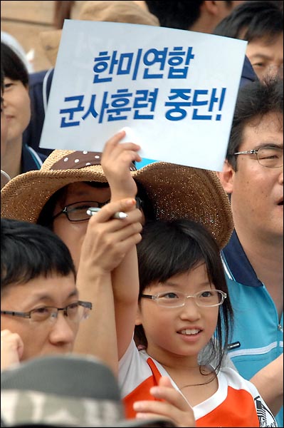 8월 15일 오후 서울역 광장에서 개최된 '광복 65년 천안함 진실규명 한반도 평화실현 8.15대회'에서 한 어린아이가 "군사훈련 중단"을 요구하는 선전물을 들어보이고 있다.