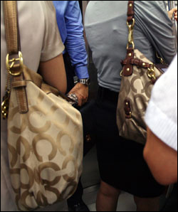 퇴근시간대 지하철 3호선 열차 안에 같은 명품가방을 든 여성 두명이 서있다.