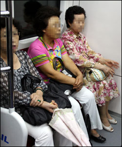 분당선 열차 노약자석에 곱게 꾸민 할머니 세분이 앉아 있다.