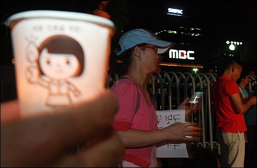 김재철 사장이 'PD수첩-4대강 수심 6m의 비밀' 편을 방송보류 결정을 내린 가운데 17일 밤 서울 여의도 MBC 사옥 앞에 모인 시민들이 방송 불방사태에 항의하며 촛불을 들어보이고 있다.