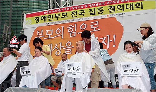 장애자녀를 둔 부모들이 31일 오후 서울 종로구 보신각 앞에서 열린 '장애인부모 전국집중결의대회'에서 장애인 복지 예산 확보와 장애아동 및 발달장애인의 권리보장을 촉구하며 삭발을 하고 있다.