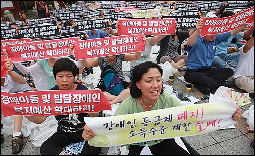 31일 오후 서울 종로구 보신각 앞에서 열린 '장애인부모 전국집중결의대회'에서 참석자들이 장애인 복지 예산 확보와 장애아동 및 발달장애인의 권리보장을 촉구하며 손피켓을 들어보이고 있다.