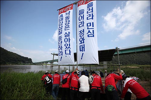  '4대강 사업 중단 촉구 낙동강 700리 뗏목 대장정'을 시작하는 대구경북 골재노조원들이 13일 오전 경북 예천 삼강주막 부근 낙동강변에서 '흘러라 민심, 들어라 청와대' '낙동강은 살아있다. 4대강 삽질 중단하라!'는 현수막을 붙인 뗏목을 강에 넣고 있다.