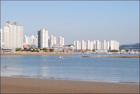  멀리서 바라본 월곶포구. 그 앞으로 배 한 척이 지나가고, 배경으로 아파트 단지가 들어서 있다.