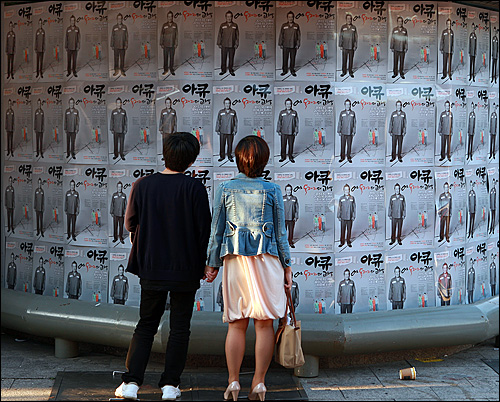  30일 저녁 서울 마포구 홍대 앞 '예' 소극장에서 지나가는 시민들이 연극 <아큐-어느 독재자의 고백>의 포스터를 관심있게 보고 있다.
연극은 10월 1일부터 31일까지 서울 홍대 앞 '예' 소극장에서 공연된다. 