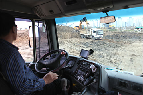 12일 오후 광주지역의 영산강 살리기 사업 현장에서 한 덤프트럭 기사가 앞서 흙 운반 작업에 나선 덤프트럭을 쳐다보고 있다.