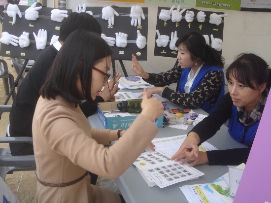 젊은 남녀 두명이 통역사와 열심히 수어(수화)를 배우고 있다.

