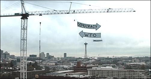  시애틀 시가지가 한 눈에 내려다보이는 타워 크레인에 민주주의와 WTO가 정반대로 가는 화살표 모양의 펼침막이 바람에 휘날리고 있다.