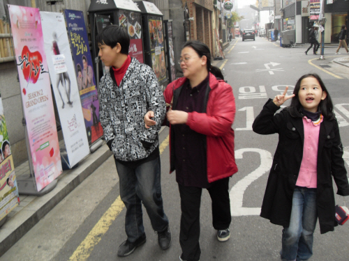 대학로의 연극포스터를 구경하며 걷는 가족.