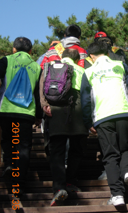 봉사활동 녹색 쪼기를 입고 계단을 오르고 있는 조합원들.