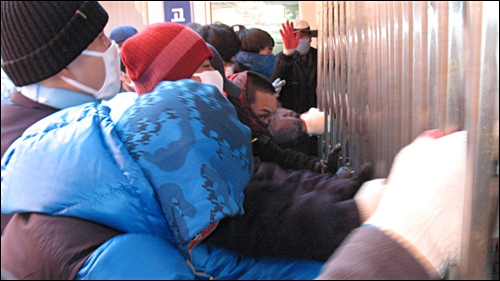 20일 공장 밖에서 농성 중이던 노동자들이 사측이 노조가 점거 중인 1공장으로 진입을 시도한다는 소식을 듣고 공장 안으로 들어가기 위해 철문을 뜯어 내려 하고 있다.