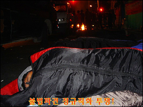 6일간 파업 농성에 참가하느라 피곤한 비정규직 노동자가 추운데도 깊이 잠들어 있습니다.