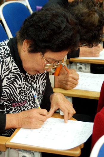 안경을 두개나 겹쳐 쓴 참가자가 경필대회에 참여하고 있는 모습.