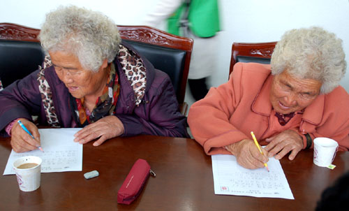 고덕 사리경로당 문해교실에서 나란히 공부하는 할머니 자매가 편지를 쓰고 있다.
